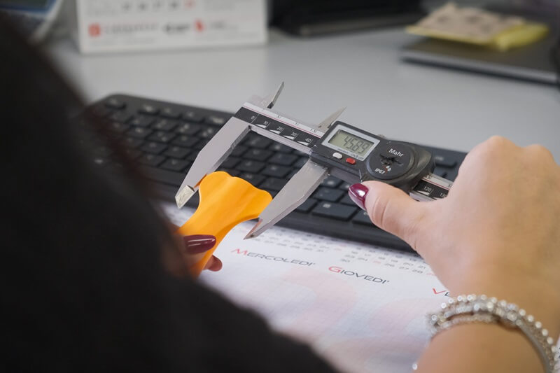 Operatore controlla la qualità della stampa con un calibro digitale